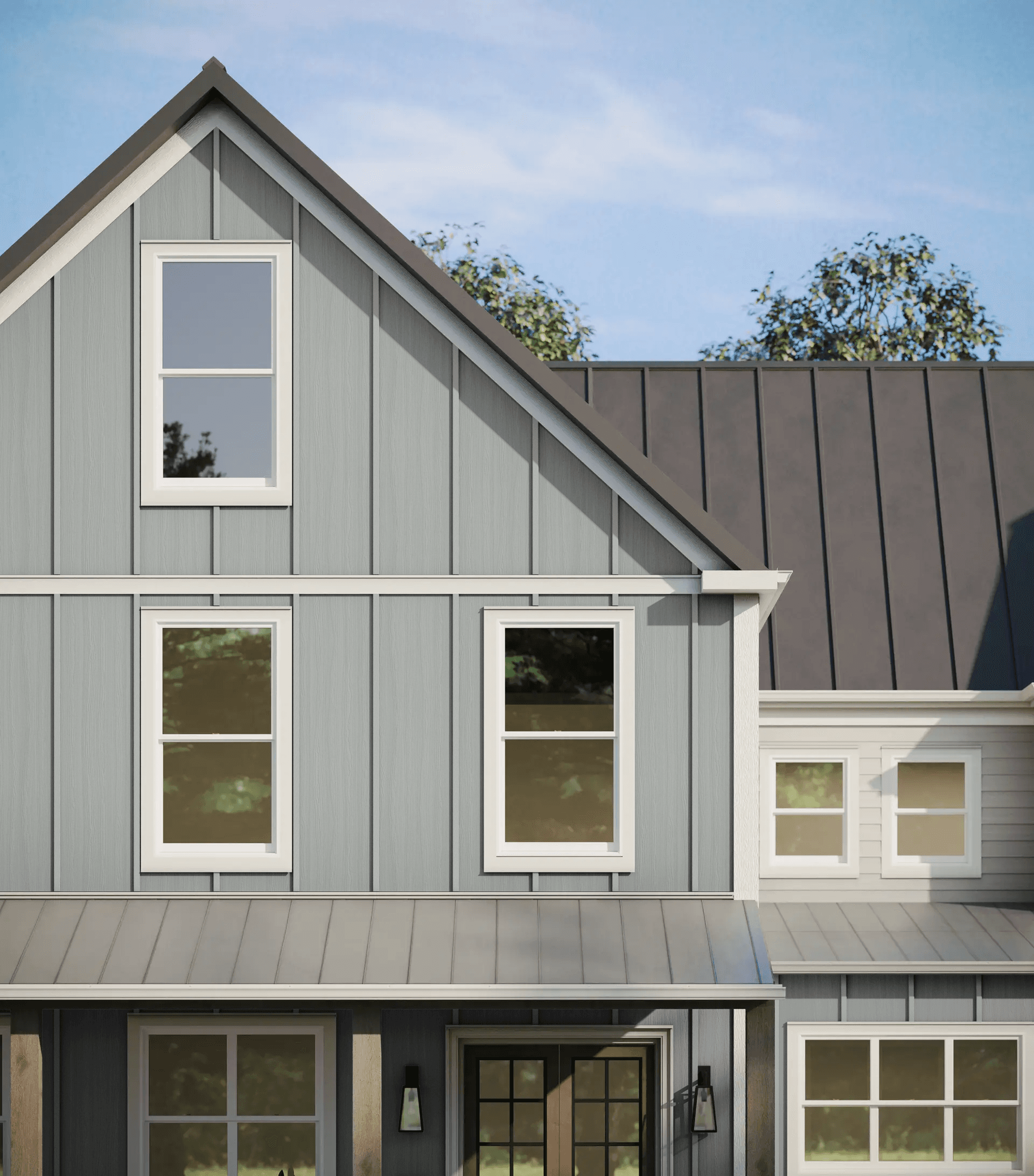 Close-up of a modern gray house with vertical siding, a dark metal roof, and white-framed windows under a clear blue sky. Trees are in the background.